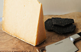 cheshire appleby cheese with charcoal artisan biscuits on a wooden paxton and whitfield cheeseboard with cheese knife