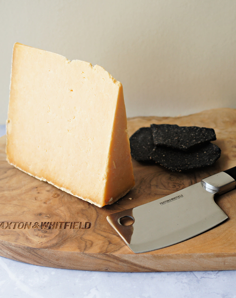 cheshire appleby cheese with charcoal artisan biscuits on a wooden paxton and whitfield cheeseboard with cheese knife