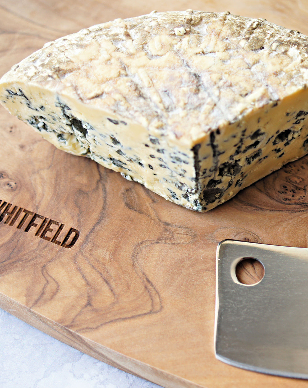 close up of barkham blue cheese on a paxton and whitfield wooden cheeseboard 