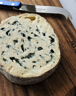 close up of fourme d'ambert blue cheese on paxton and whitfield wooden cheeseboard and cheese knife