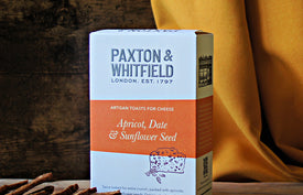 box of paxton and whitfield apricot date and sunflower seed artisan toasts for cheese on wooden cheeseboard