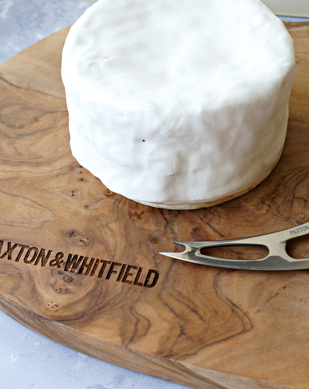 close up of whole brillat savarin affine on paxton and whitfield wooden cheeseboard