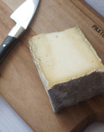 close up of caerphilly gorwydd cheese on a wooden paxton and whitfield cheeseboard