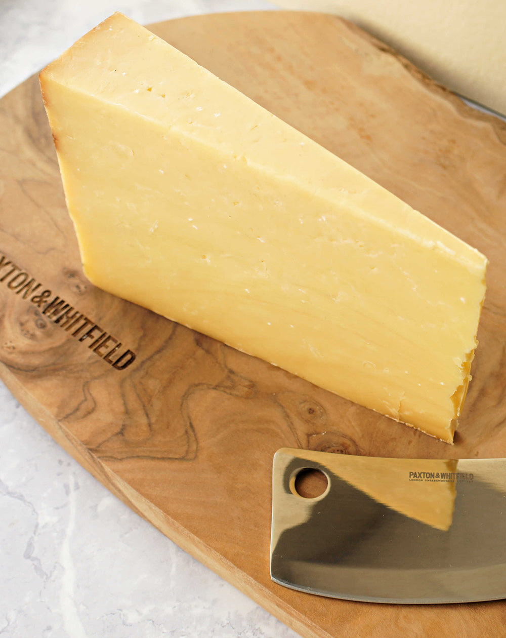 detail shot of cave aged cheddar on a wooden paxton and whitfield cheeseboard