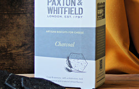 box of charcoal artisan biscuits on a wooden paxton and whitfield cheeseboard