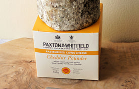 paxton and whitfield cheddar pounder cheese with box packaging on wooden cheeseboard with cheese knife